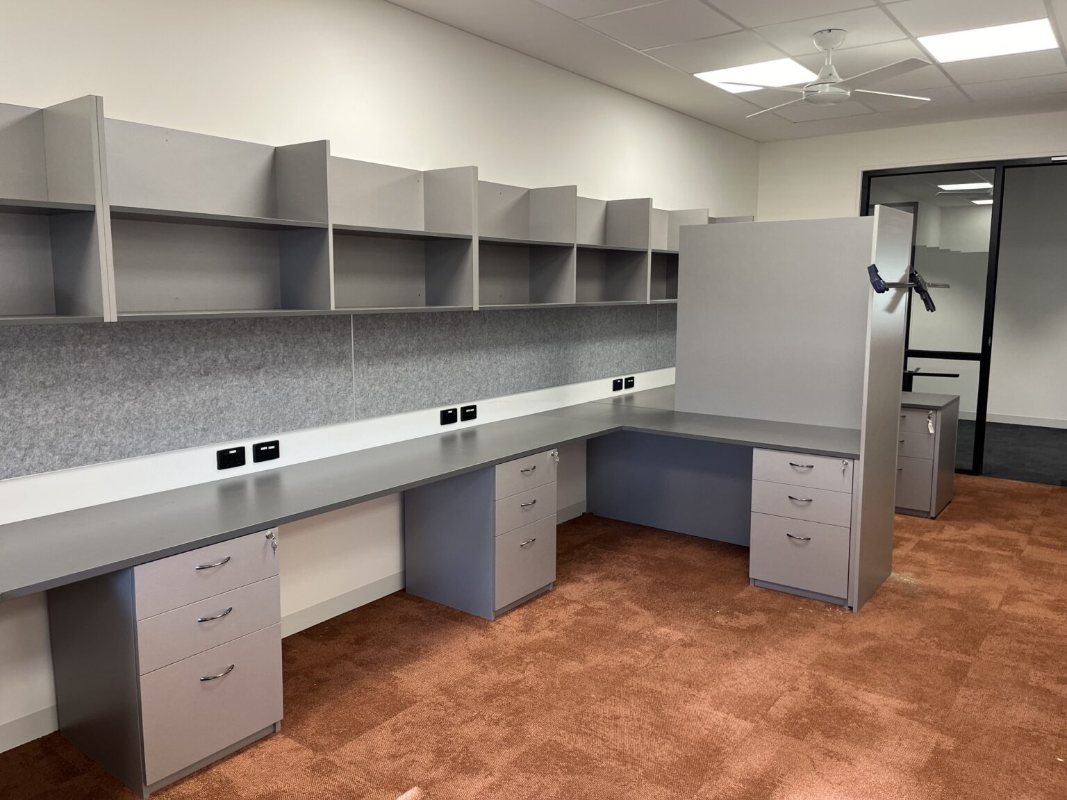 Custom grey office workstation cabinetry with overhead storage by EFI Furniture